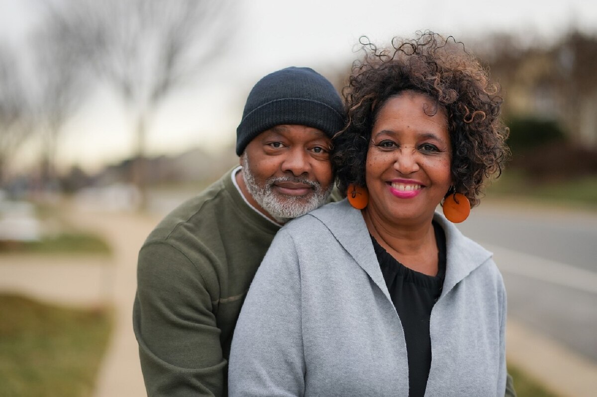 A senior couple smiles on a sidewalk.