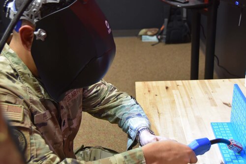 A person is wearing a welding mask and using a virtual reality interface.
