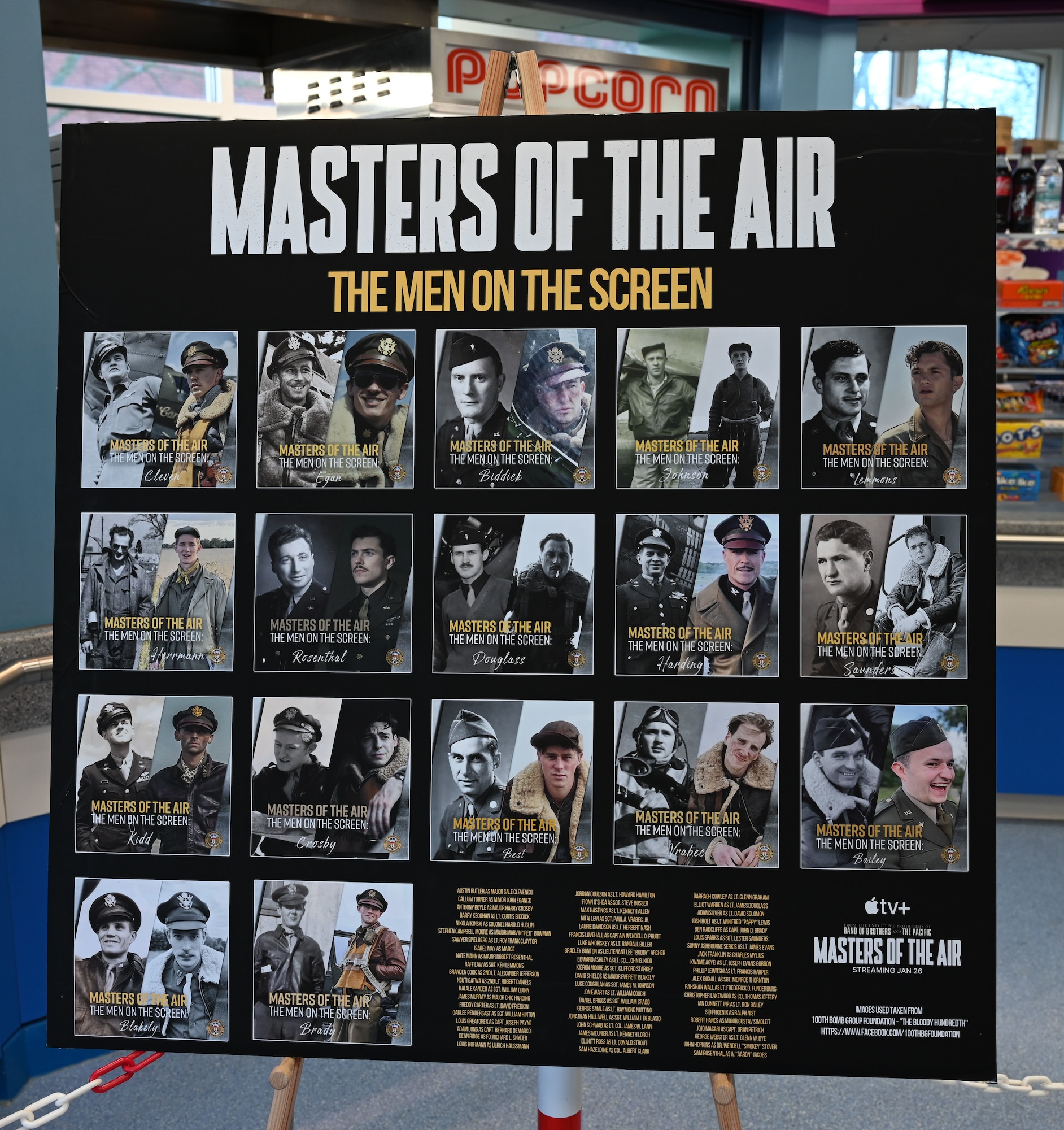 A display board showing World War II Airmen from the 100th Bomb Group, Thorpe Abbotts, England, alongside the actors portraying their characters, stands on show at a premiere of the first episode of the upcoming “Masters of the Air” miniseries at Royal Air Force Mildenhall, England, Jan. 19, 2024. The soon-to-be-released nine-part series on Apple TV+ highlights the legacy of both Eighth Air Force and 100th Bomb Group to which the 100th ARW has direct ties. (U.S. Air Force photo by Karen Abeyasekere)