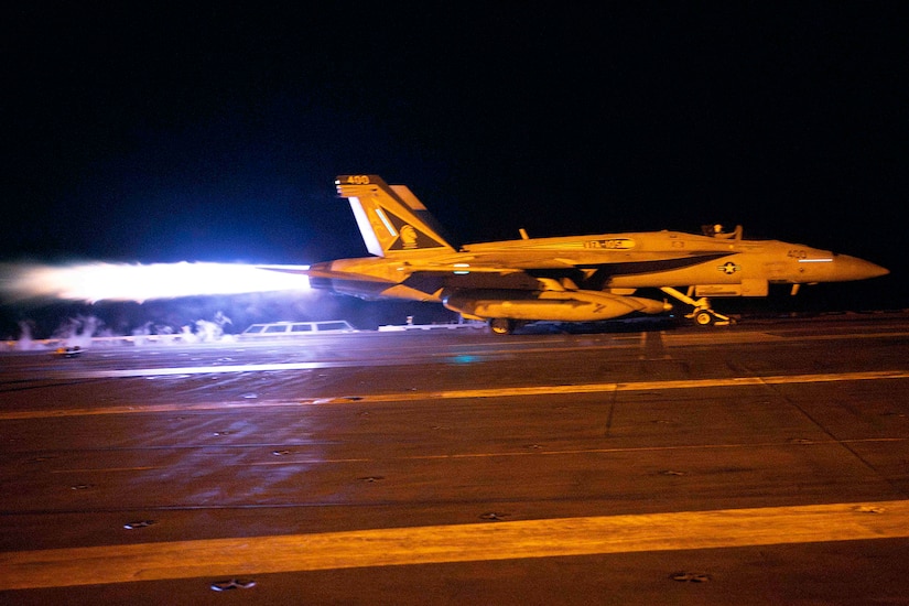 A jet launches from an aircraft carrier.