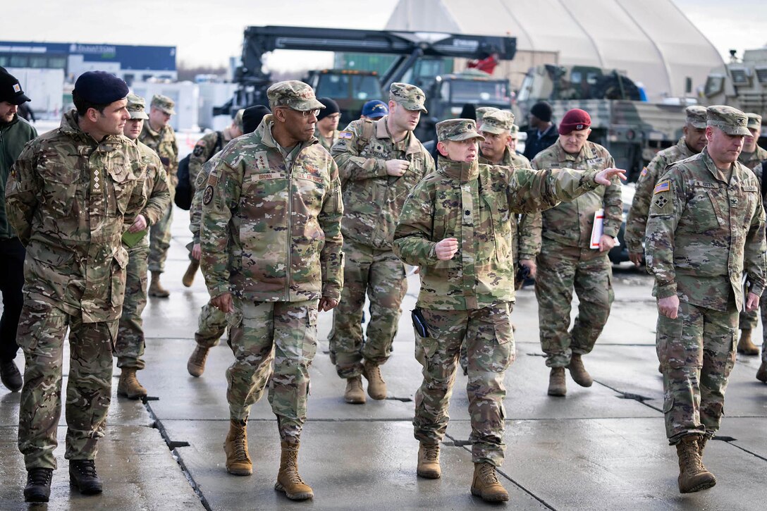 Air Force Gen. CQ Brown, Jr. walks with foreign and U.S. troops, one of whom points while speaking, at an outdoor facility.