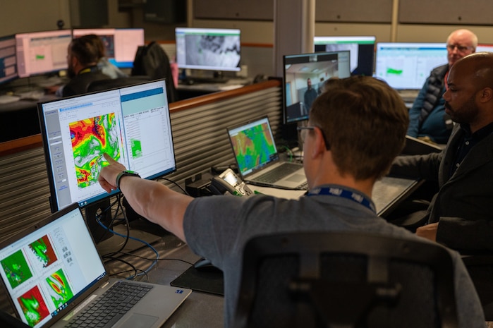 A photo of NIWC personnel pointing at a computer screen.