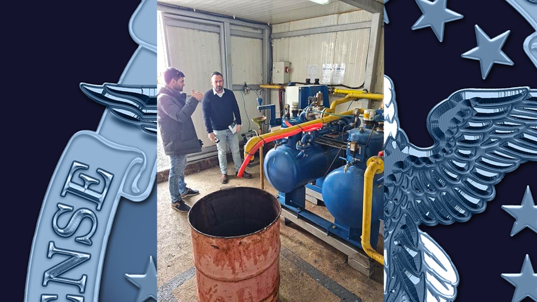 Two men look over equipment in an engineering shed.