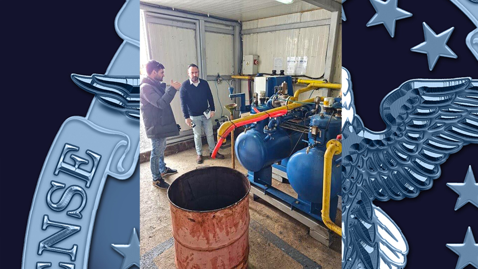 Two men look over equipment in an engineering shed.