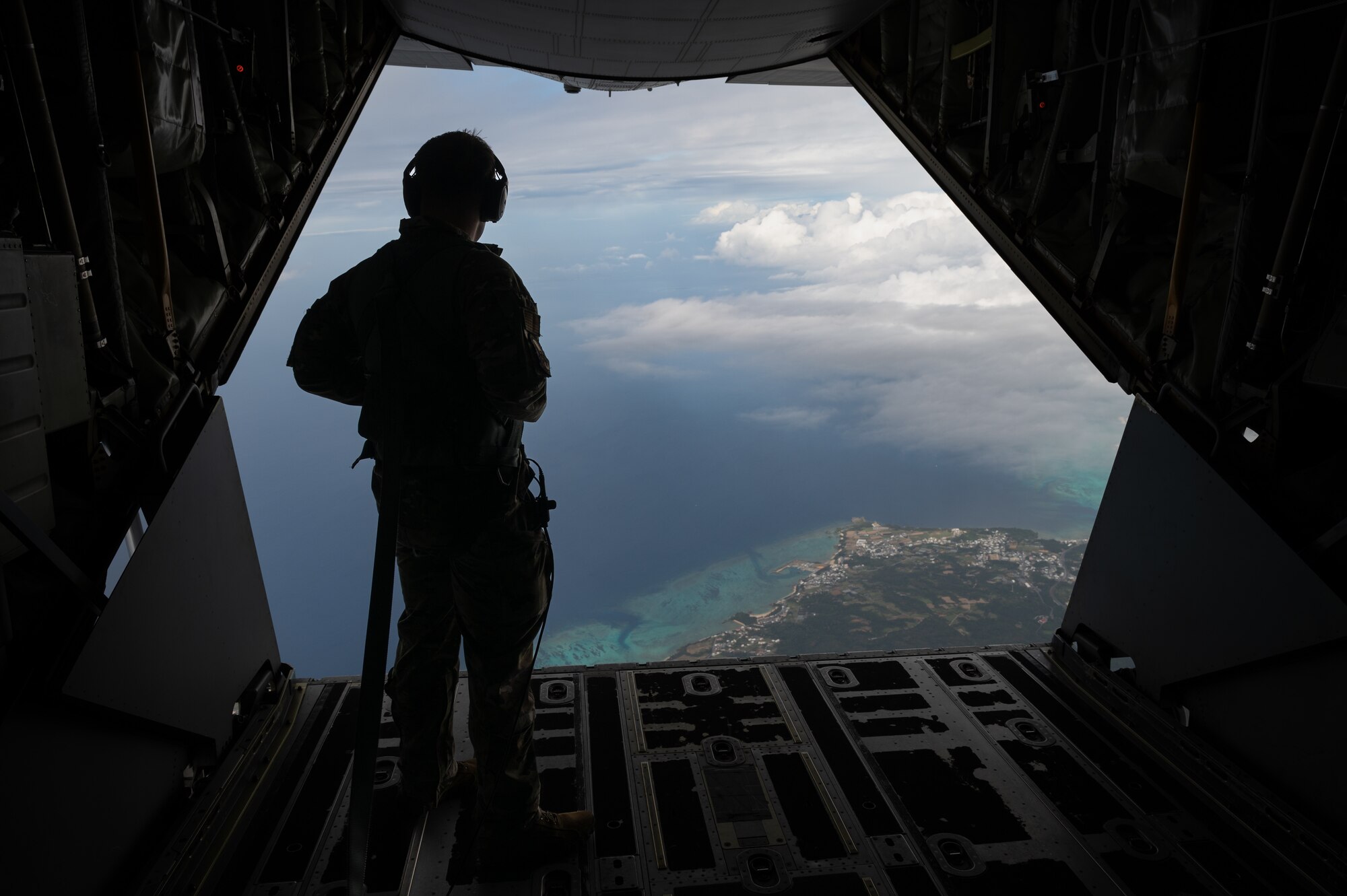 A service member looks out the back of an MC-130J