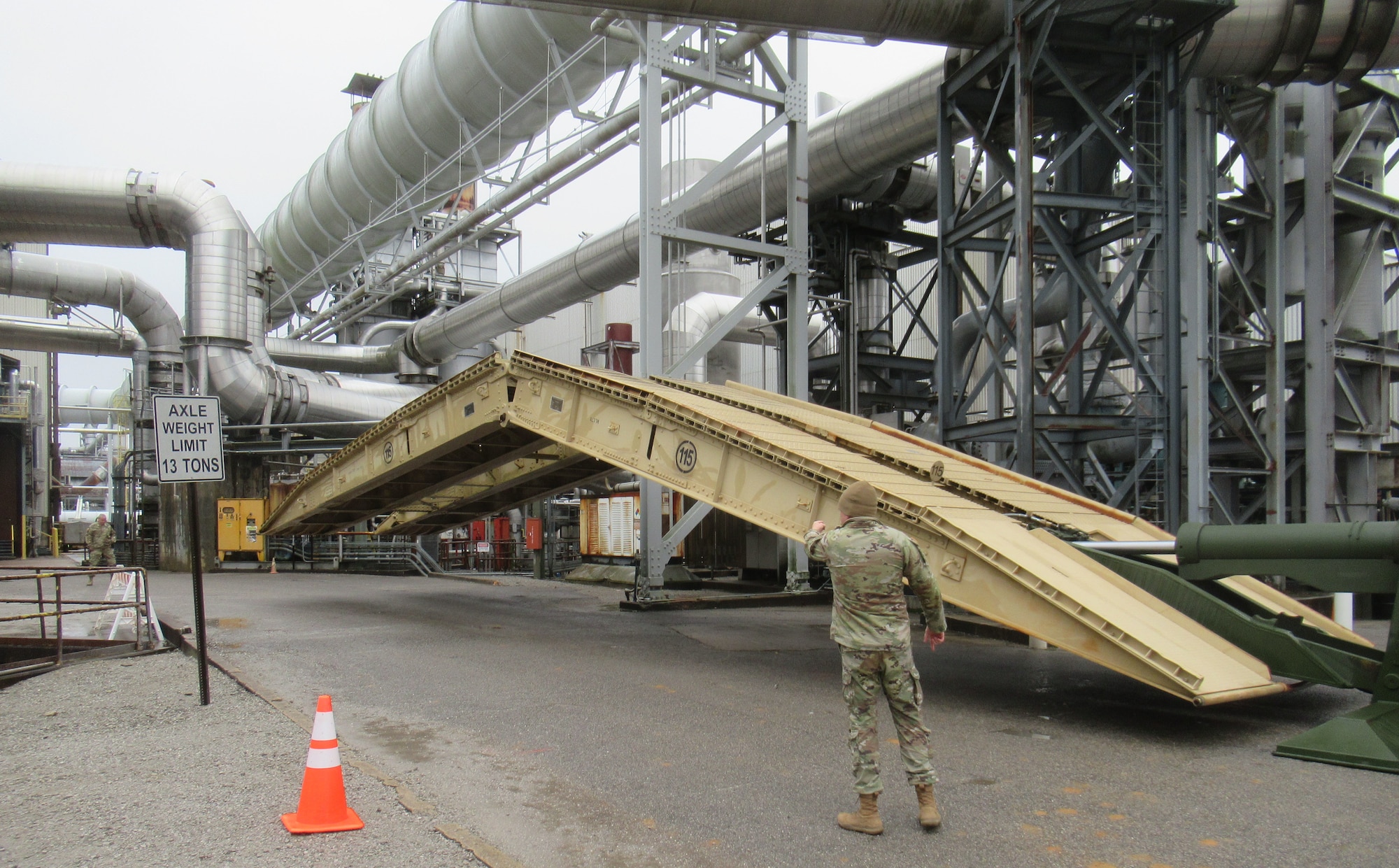 The bridge component of an Armored Vehicle Launched Bridge is emplaced Jan. 6, 2024, over the first entryway crossing into a work area at Arnold Air Force Base, Tenn. AVLBs carry a deployable bridge and are designed to allow tanks, infantry fighting vehicles and other tactical vehicles to cross small rivers, gaps and other terrain obstacles on the battlefield. The AVLB was commercially delivered to Arnold from Fort Campbell, Ky., on Nov. 30, 2023, and was needed to move a large crane across an Arnold alleyway where the axle load limit was less than the weight of the crane. The AVLB was operated by a Guardsman with the 190th Engineer Company of the Tennessee National Guard, while Guardsmen from the 194th Engineer Brigade directed and guided the operation. (U.S. Air Force photo)