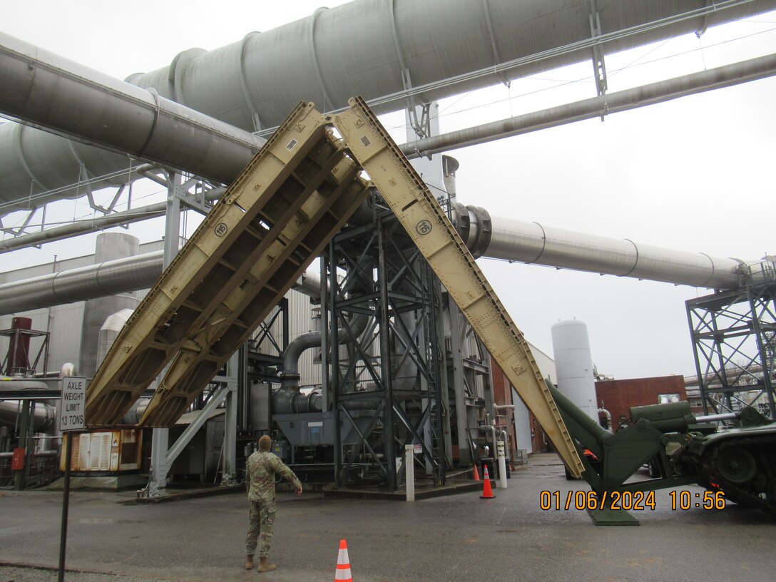 The bridge component of an Armored Vehicle Launched Bridge is put into place Jan. 6, 2024, at Arnold Air Force Base, Tenn. Extra precaution was taken to avoid striking overhead objects, something typically not present on the battlefield. Bridges were emplaced at Arnold without incident. AVLBs carry a deployable bridge and are designed to allow tanks, infantry fighting vehicles and other tactical vehicles to cross small rivers, gaps and other terrain obstacles on the battlefield. The AVLB was commercially delivered to Arnold from Fort Campbell, Ky., on Nov. 30, 2023, and was needed to move a large crane across an Arnold alleyway where the axle load limit was less than the weight of the crane. The AVLB was operated by a Guardsman with the 190th Engineer Company of the Tennessee National Guard, while Guardsmen from the 194th Engineer Brigade directed and guided the operation. (U.S. Air Force photo)