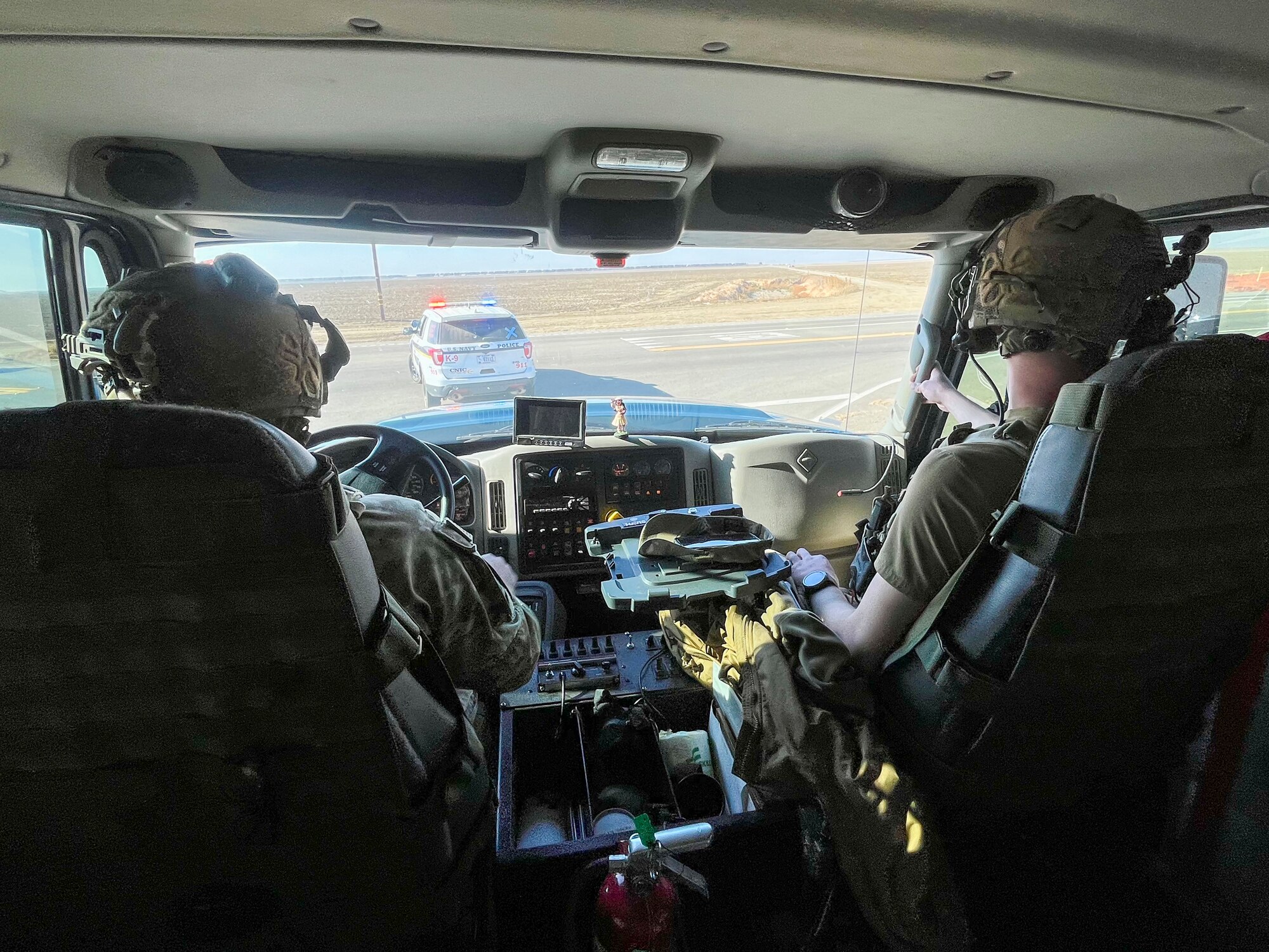 Two Airmen sit in a vehicle.