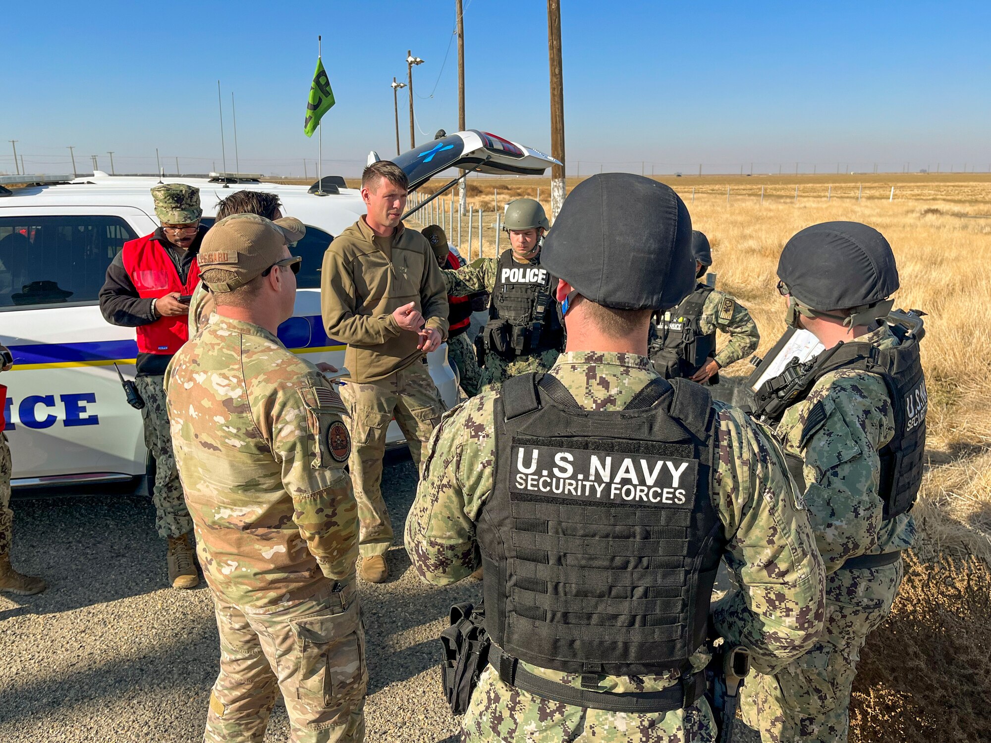 Military members stand in a circle and discuss a plan.