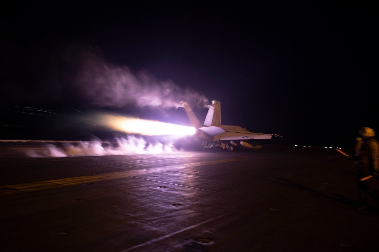 A jet launches from a aircraft carrier.