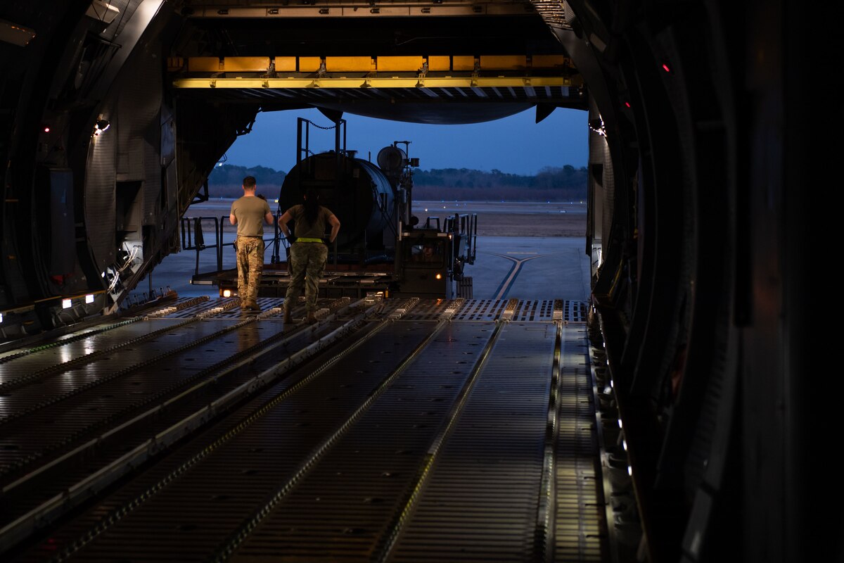 Service members stand on the ramp of a military cargo plane.