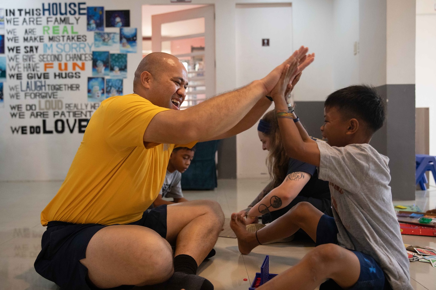 Lt. j.g. Nafetalai Teaupa, from Kailua Kona, Hawaii, assigned to the Arleigh Burke-class guided-missile destroyer USS William P. Lawrence (DDG 110), celebrates winning a board game with a child from Gentle Hands Orphanage during a community relations event in Manila, Philippines.