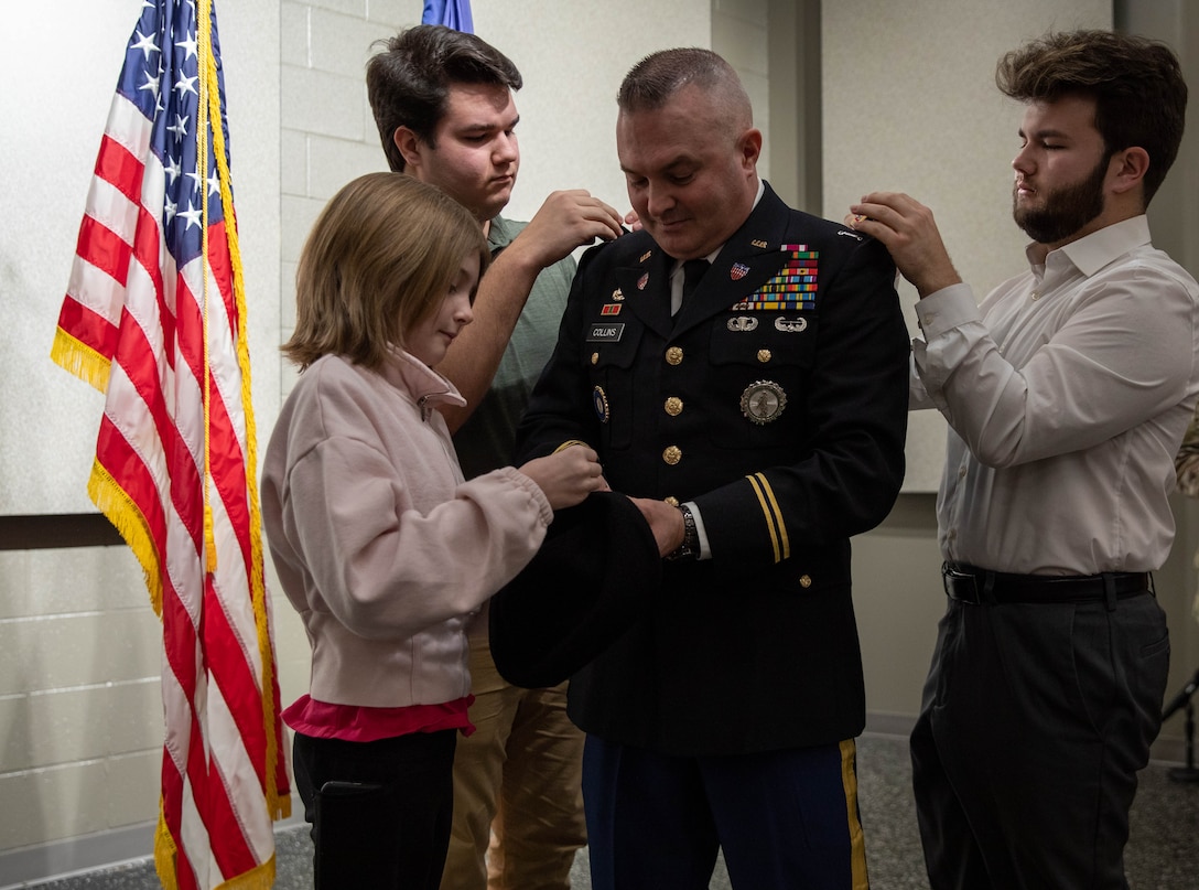 Chief Warrant Officer Four Timothy Collins' children pin on his ranks during his promotion ceremony at the Wellman Auditorium on the Boone Center in Frankfort, Kentucky Jan. 22, 2024