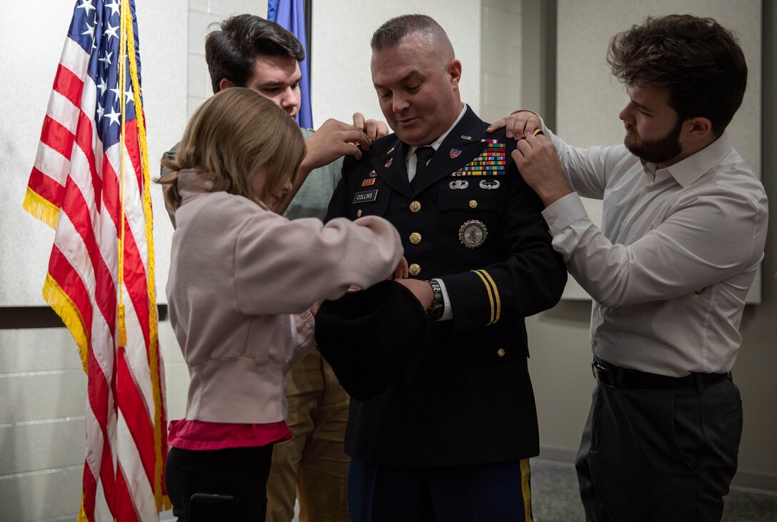 Chief Warrant Officer Four Timothy Collins' children pin on his ranks during his promotion ceremony at the Wellman Auditorium on the Boone Center in Frankfort, Kentucky Jan. 22, 2024