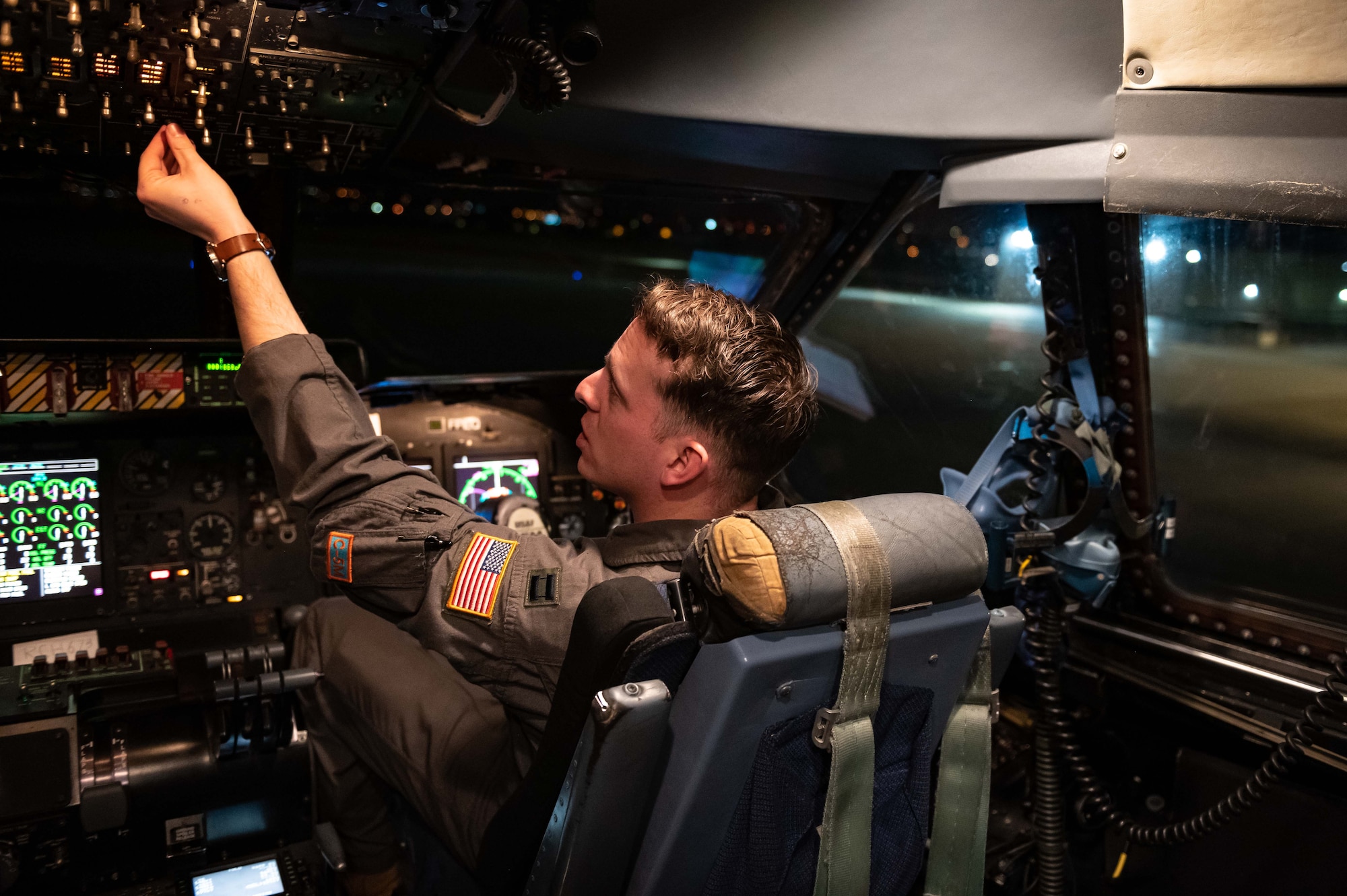 A pilot reaches for a switch in the cockpit