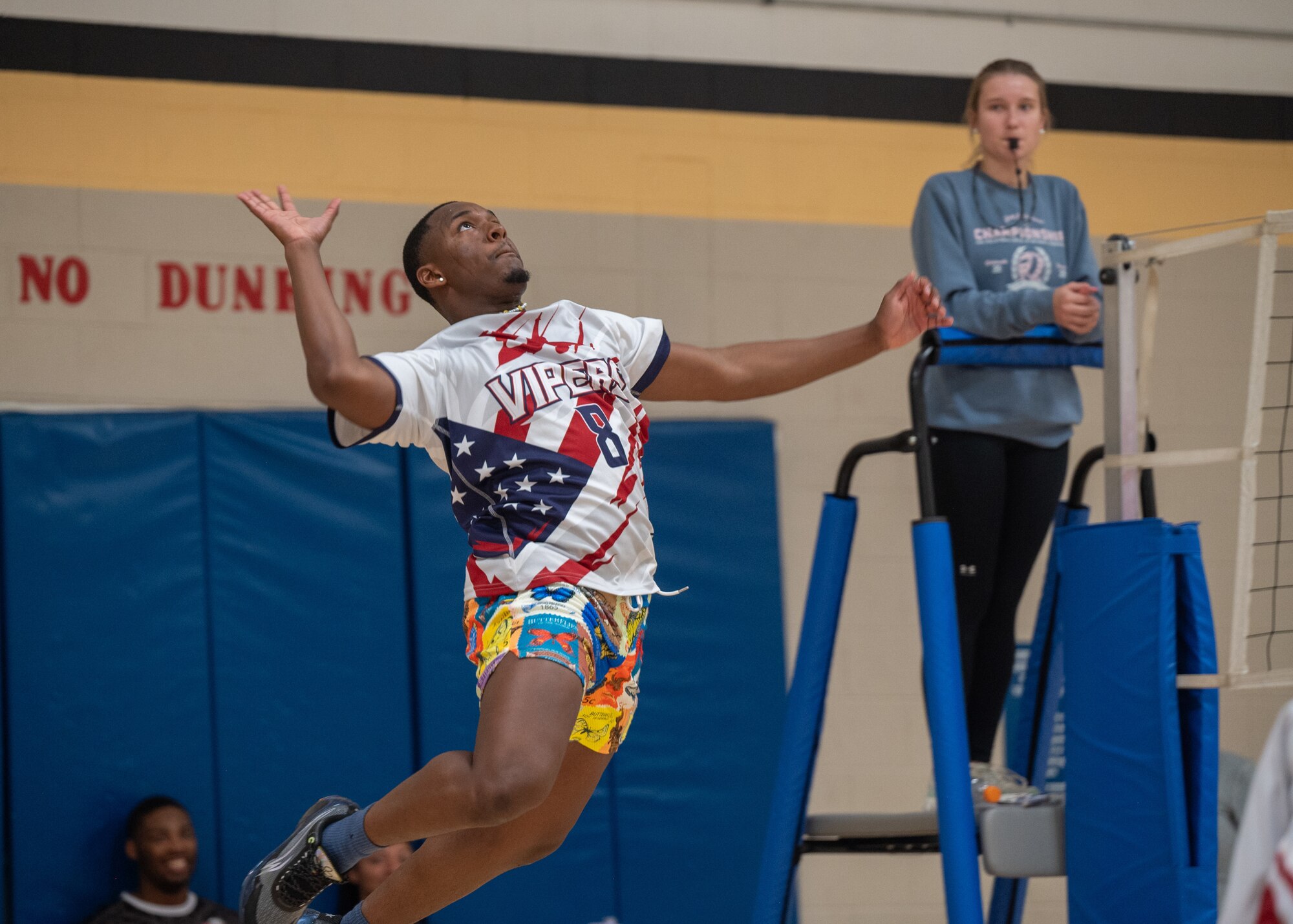 A volleyball player jumps in the air to hit the ball over the net