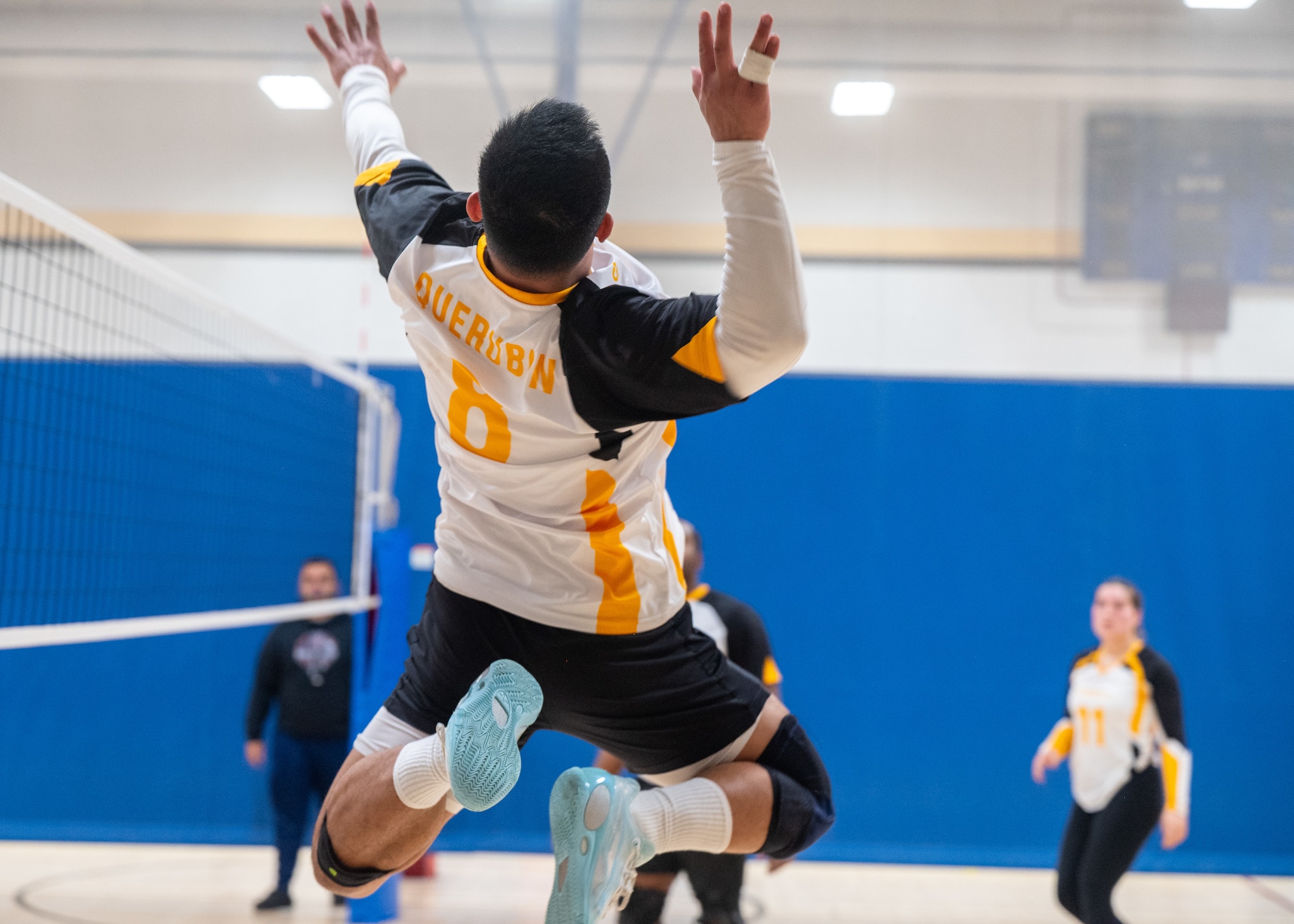 A volleyball player jumps to hit the ball over the net