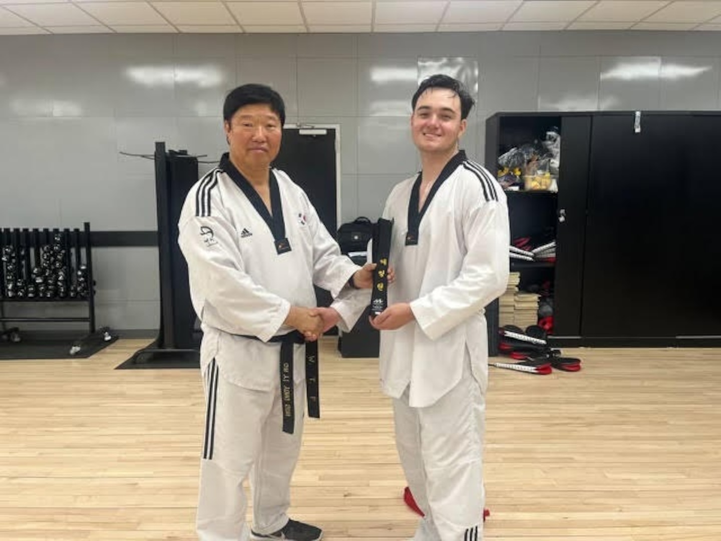 Yi Yong-son (left), a 7th degree Taekwondo black belt, presents a black belt to Sgt. Robert J. Errington (right) from the 59th Chemical, Biological, Radiological, Nuclear (CBRN) Company (Hazards Response). Errington earned his black belt in six months. Courtesy photo.