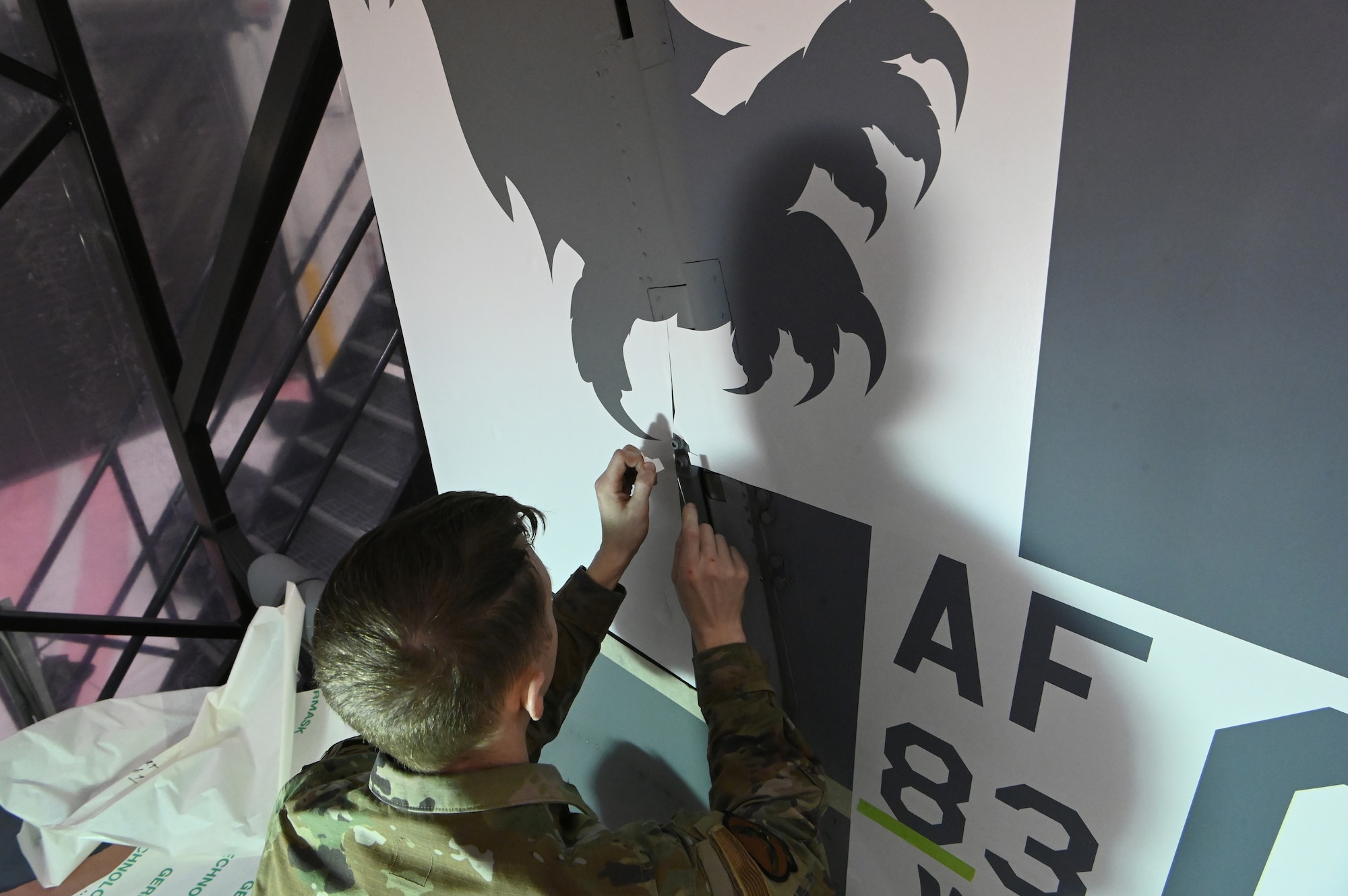 U.S. Air Force Staff Sgt. Sean Green, a structural maintenance technician with the 550th Fighter Squadron, carefully trims the first set of stencils forming the eagle that will adorn the 173rd Fighter Wing F-15C.
