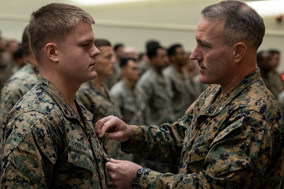 U.S. Marines Corps Lt. Col. Andrew Nicholson, right, presents a Navy and Marine Corps Commendation Medal to Cpl. Jacob Cogswell, left, during an award ceremony at the base theater on Camp Schwab, Okinawa, Japan, Jan. 12, 2024. The ceremony was held to award Sgt. Aidan Blansfield and Cpl. Jacob Cogswell with Navy and Marine Corps Commendation Medals for life saving acts while on pre-deployment leave. Both Marines awarded rescued a civilian from drowning. Nicholson, a native of South Carolina, is the battalion commander and Cogswell, a native of New York, is a machine gunner, both with of 2d Battalion, 2d Marine Regiment. 2/2 is currently forward deployed in the Indo-Pacific under 4th Marine Regiment, 3d Marine Division as part of the Unit Deployment Program. (U.S. Marine Corps photo by Cpl. Eduardo Delatorre)