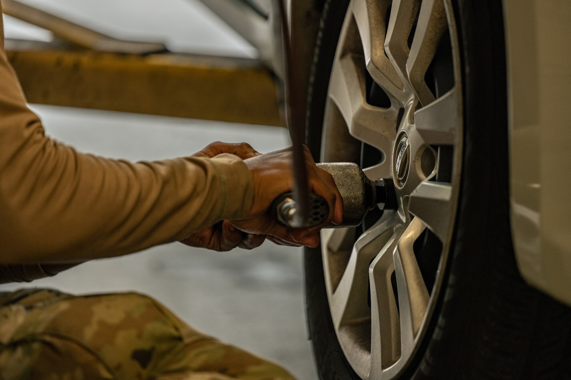 U.S. Air Force Senior Airman Zaire Pitts, a 4th Aircraft Maintenance Unit crew chief, uses an air drill to remove lug nuts from a wheel at the Auto Hobby Shop.