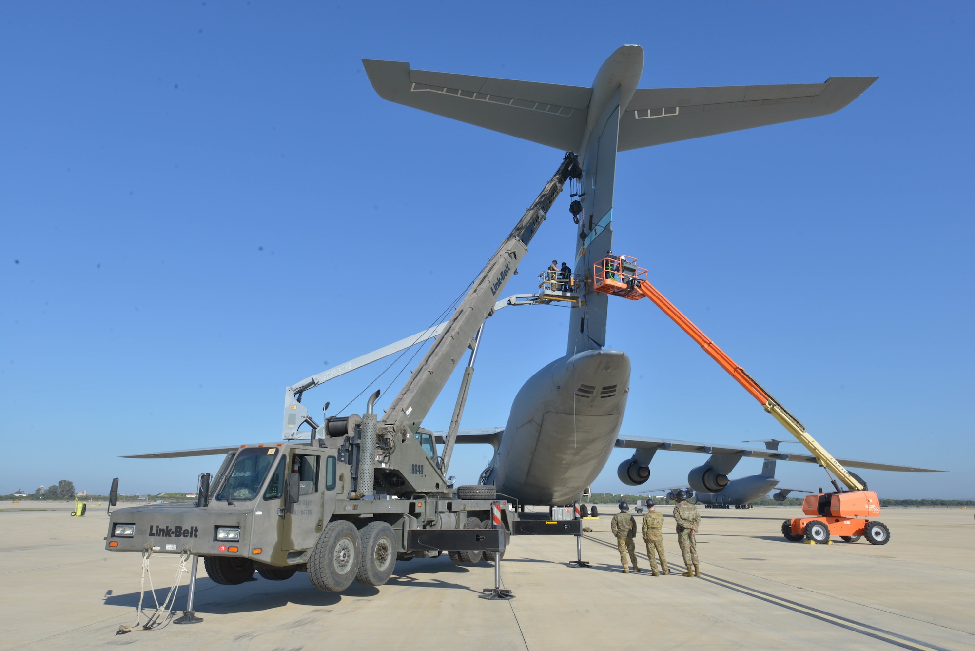 230106-N-NO901-1037 NAVAL STATION ROTA, Spain (Jan. 6, 2023) – Seabees assigned to Naval Mobile Construction Battalion (NMCB) 11 and Airmen assigned to  the 436th Maintenance Squadron work together to remove the rudder of a C-5M Super Galaxy with NMCB 11's Link-Belt HTC8640 Cat 1 Crane onboard Naval Station Rota, Spain, Jan. 6, 2023.