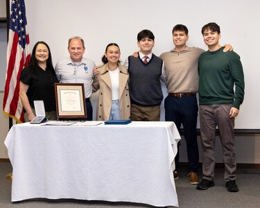 Chris Hughes, carrier program manager, Code 312, Aircraft Carrier Program Office at Puget Sound Naval Shipyard & Intermediate Maintenance Facility, poses with his wife, Julie, and their four children (from left), Katie, Joseph, Charles and Nicholas, Dec. 21, 2023, after receiving the Navy Superior Civilian Service Award during a ceremony at PSNS & IMF, in Bremerton, Washington. (U.S. Navy photo by Wendy Hallmark)