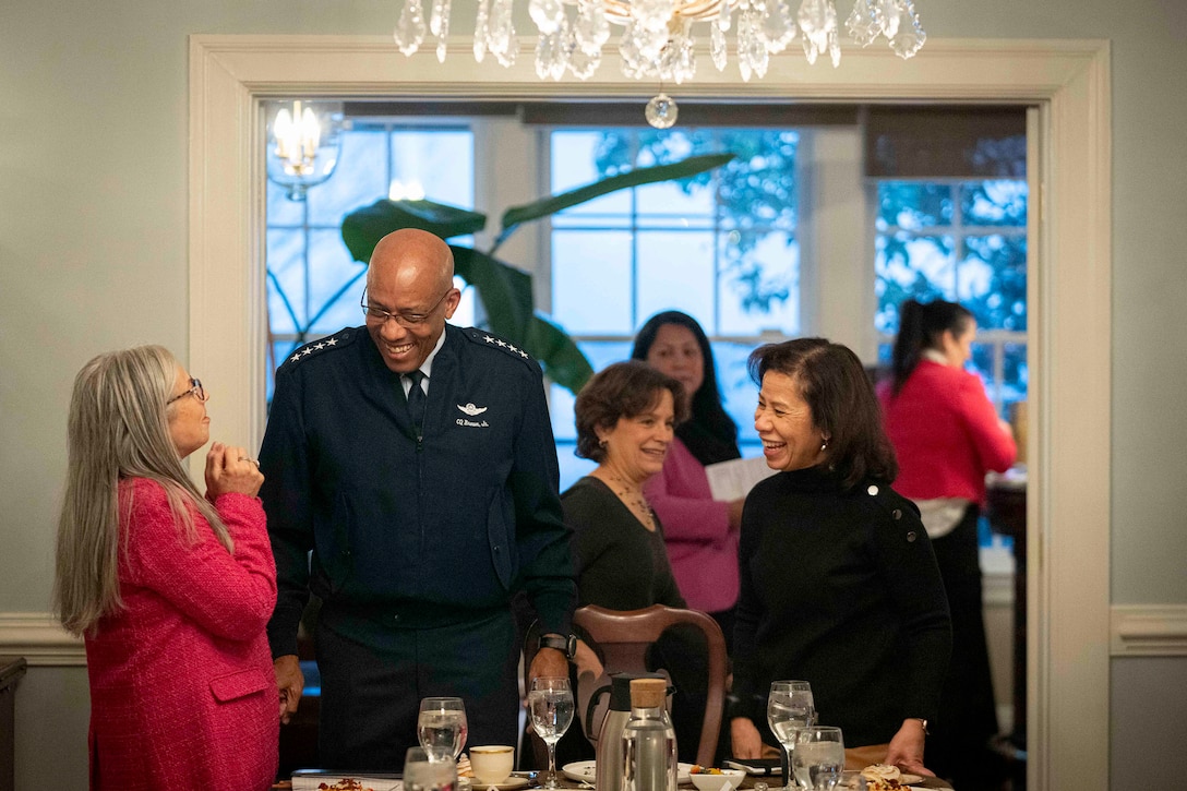 Air Force Gen. CQ Brown, Jr. and his wife smile and speak with civilians standing by a set table in a dining room.