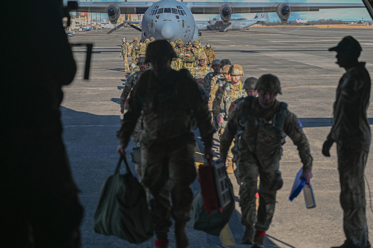 Military personnel board an aircraft.