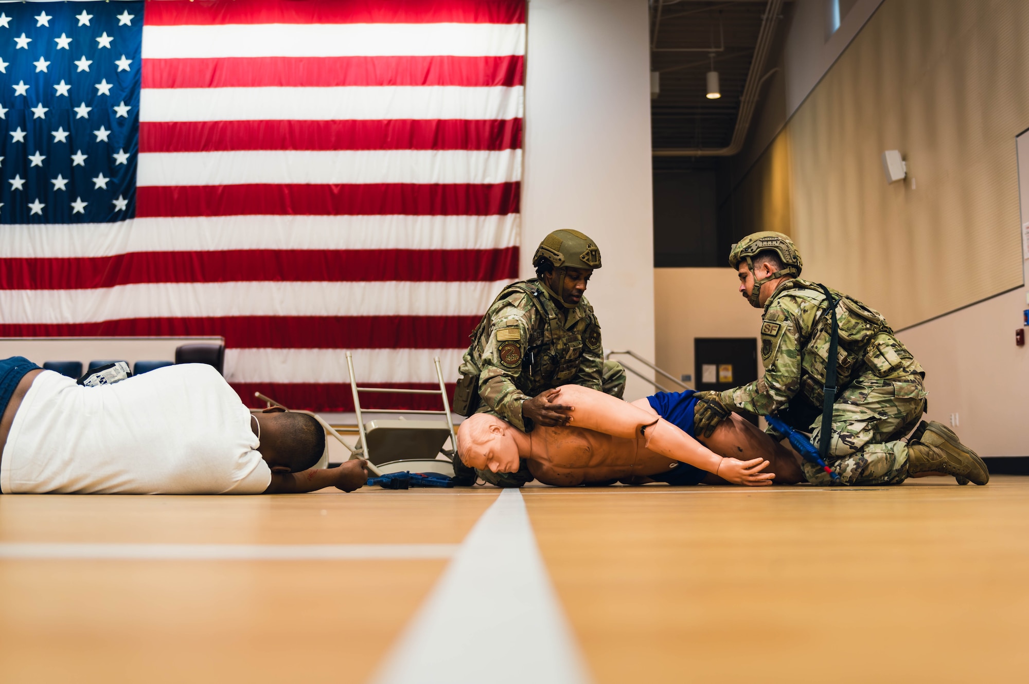 William Anderson (left), 56th Security Forces Squadron defender, and Tech Sgt. Jacob Sime (right), 56th SFS defender, perform a simulated emergency medical examination on a simulated injured victim during an active shooter exercise.