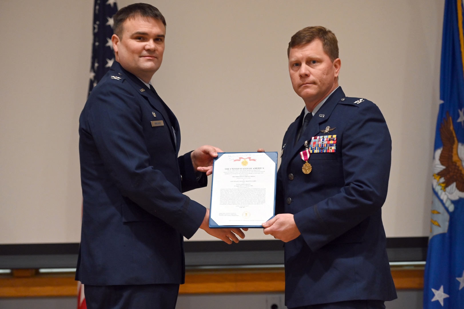 Col. Richard Wallace, 960th Cyberspace Operations Group commander, and Col. Shaun Zabel present the awarded certificate for the Meritorious Service Medal for Zabel’s outstanding service as 960th Cyberspace Operations Group deputy commander at Joint Base San Antonio-Kelly Annex, Texas on Jan. 6, 2024. (U.S. Air Force photo by 2d Lt Alex Dieguez)