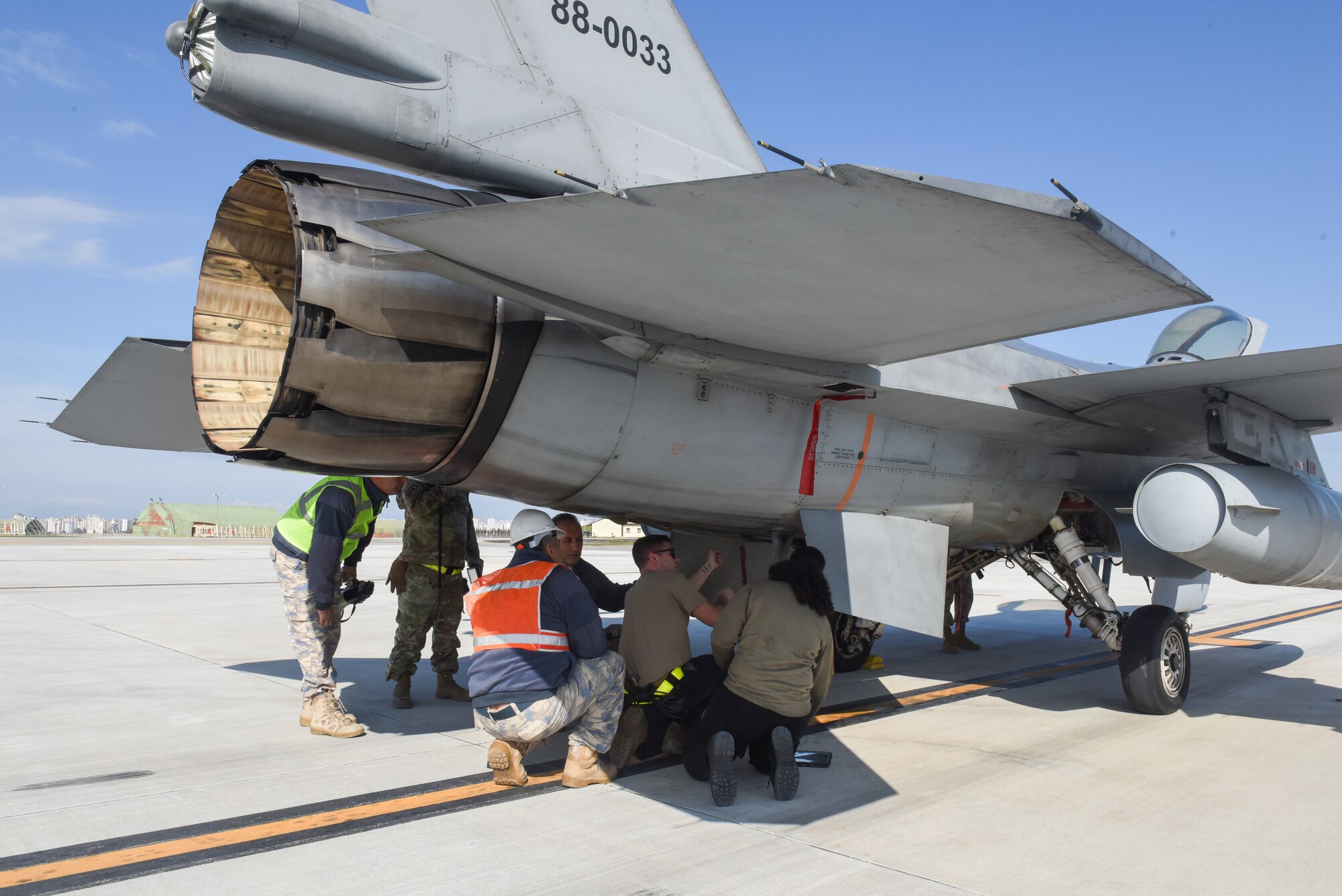 Turkish and American military members inspect the underside of an F16 fighter jet