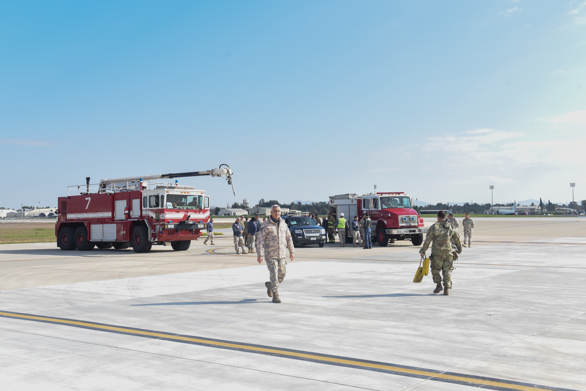 Turkish and American military members gathered around firetrucks on a flight line