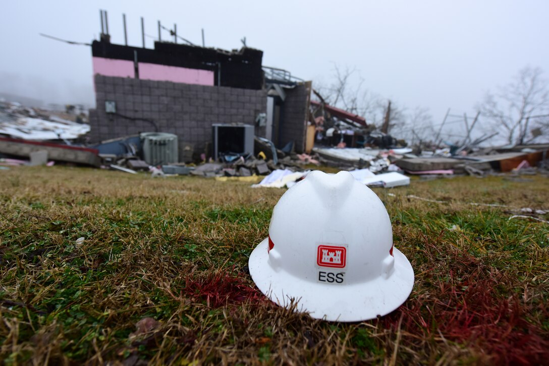 A USACE hard hat sits in the grass nearby the Electronic Service Section Building Jan. 25, 2024, that was demolished when a tornado struck the area Dec. 9, 2023. U.S. Army Corps of Engineers Nashville District employees have begun a lengthy response effort to make repairs and rebuild. (USACE Photo by Lee Roberts)