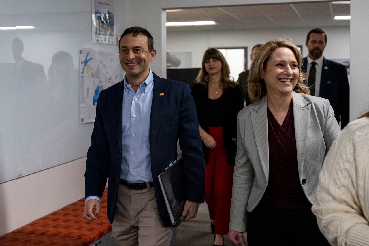 A group of people smile while walking in a hallway.