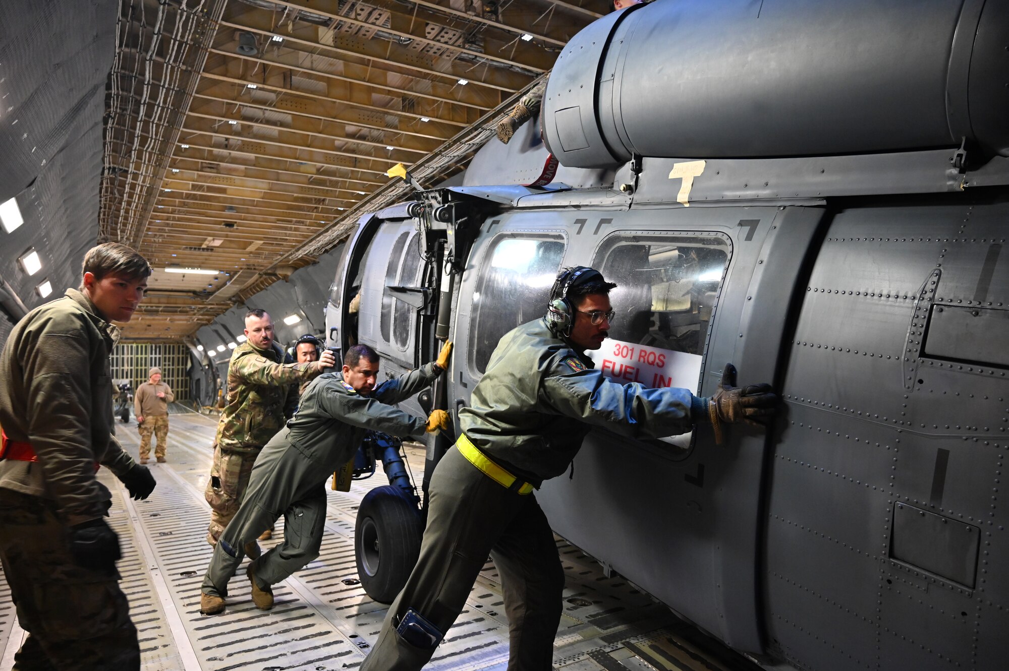 Senior Airman Ali Gundogdu, center, 68th Airlift Squadron loadmaster, offload a HH-60G Pave Hawk from the 920th Rescue Wing off a C-5M Super Galaxy and onto the flightline at Davis-Monthan Air Force Base to be retired at the 309th Aerospace Maintenance and Regeneration Group, Arizona, Jan. 19, 2024.
