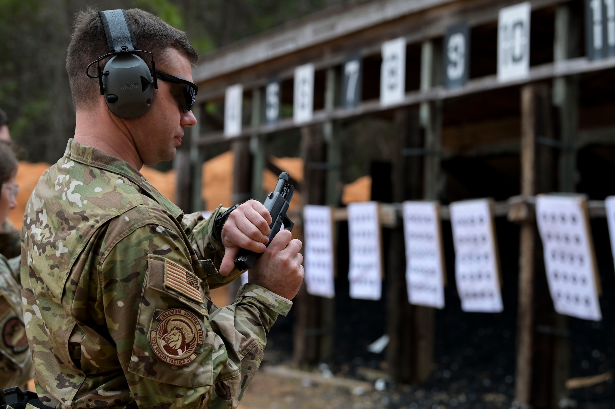 A U.S. Air Force Air Commando chambers a round into his pistol.