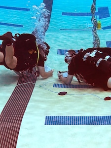 A photo of two Army divers in a swimming pool.