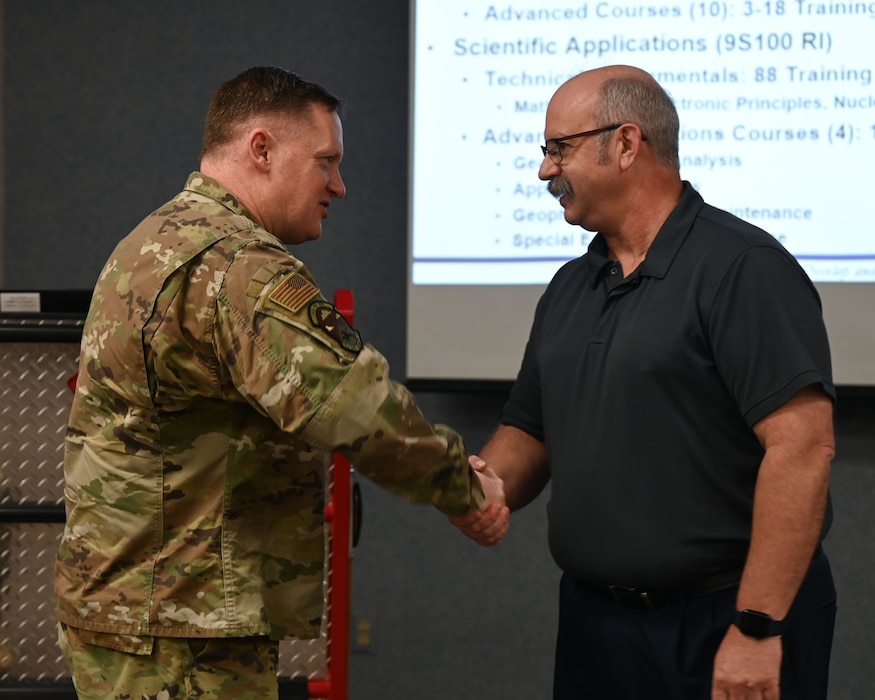 U.S. Air Force Brig. Gen. William Kale, Air Force Civil Engineer Center commander, shakes hands with Mr. Bryn Crandall, 312th Training Squadron chief of training development, to present him a coin. AFCEC oversees all CE requirements across the Air Force, including facility investment planning, design and construction, operations support, property management and oversight, energy support, environmental compliance and restoration, and readiness and emergency management. (U.S. Air Force photo by Airman 1st Class Evelyn D’Errico)