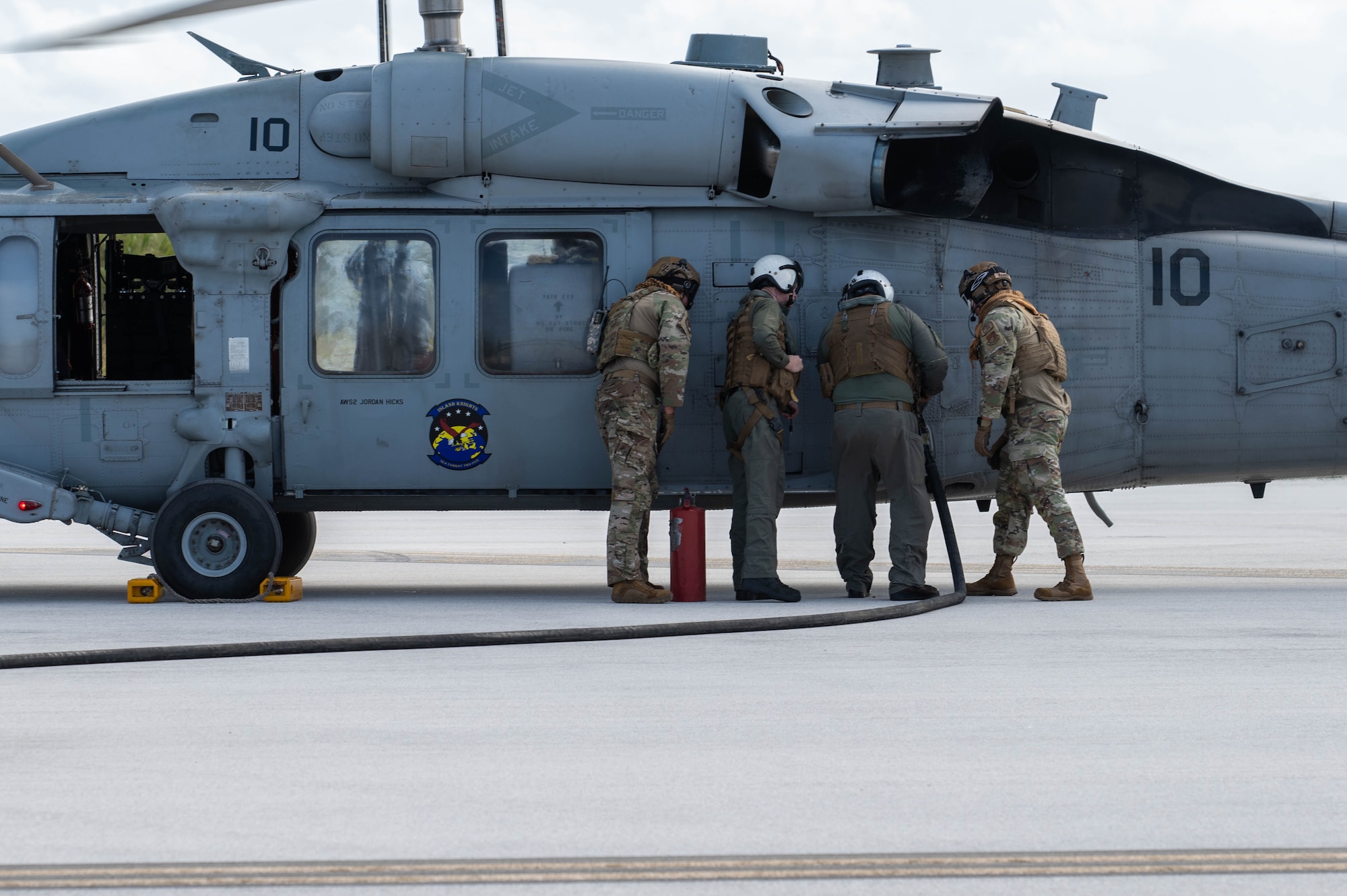 U.S. Seamen assigned to the Helicopter Sea Combat Squadron 25 (HSC-25)work with U.S. Airmen assigned to the 36th Contingency Response Squadron to refuel the H-60 Sea Hawk helicopter at Pacific Regional Training Center - Andersen, Guam, Jan. 23, 2024. The HSC-25, Marine Air Traffic Control Mobile Team (MMT) and the 36th Contingency Response Squadron all participated in a joint training on refueling operations. (U.S. Air Force Photo by Airman 1st Class Allon Lapaix)