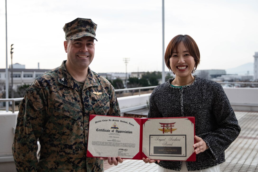 U.S. Marine Corps Col. Richard Rusnok, left, the commanding officer of Marine Corps Air Station Iwakuni, and Akiko Takemoto, an employee of the Marine Corps Air Station Iwakuni property department, pose for a photo following an Impact Iwakuni award presentation at MCAS Iwakuni, Japan, Jan. 18, 2024. The Impact Iwakuni award is presented monthly to recipients that make a significant positive impact on the community, and Akiko Takemoto won the award for leading and coordinating volunteer efforts and donations for a local animal shelter. (U.S. Marine Corps photo by Lance Cpl. Colin Thibault)