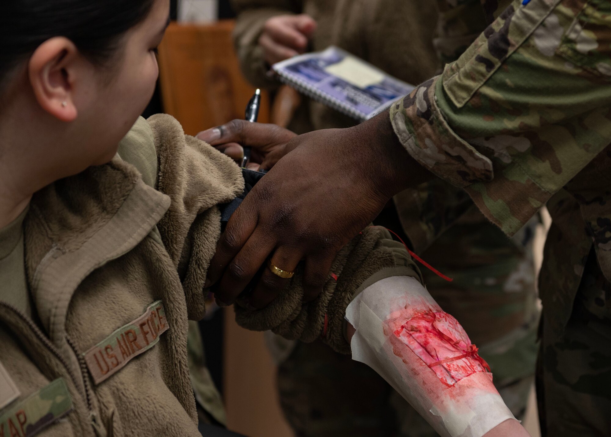 U.S. Air Force Staff Sgt. Angelica Yap, 51st Comptroller Squadron financial operations supervisor, receives tactical combat casualty care from Senior Airman Maaliq Williams, 51st Comptroller Squadron finance customer service technician, during Beverly Midnight 24-1 at Osan Air Base, Republic of Korea, Jan. 29, 2024. During TCCC training, service members learn the MARCH algorithm: massive bleeding, airway, respiration, circulation and hypothermia/head injuries. MARCH provides the order in which the life-saving skills should be applied. This affords a better opportunity to work as a team to make sure combat injuries are treated both quickly and properly. (U.S. Air Force photo by Staff Sgt. Aubree Owens)