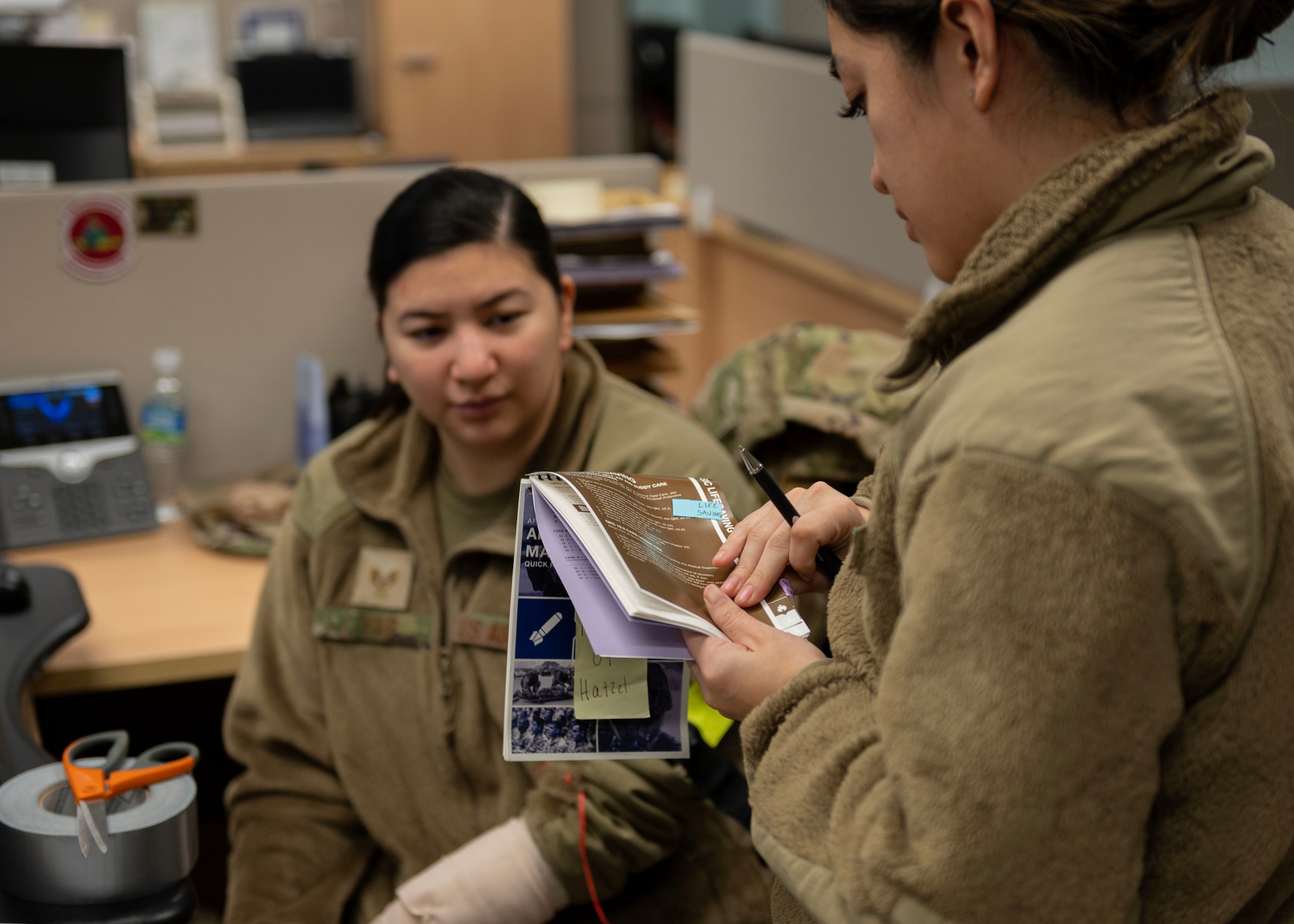 U.S. Air Force Staff Sgt. Riciel Sobreo, 51st Comptroller Squadron resource advisor, right, confirms all steps were completed with an Airman’s Manual after conducting tactical combat casualty care on a patient, Staff Sgt. Angelica Yap, 51st CPTS financial operations supervisor, during Beverly Midnight 24 at Osan Air Base, Republic of Korea, Jan. 29, 2024. The Airman's Manual provides individual Airmen with the basic tactics, techniques, and procedures necessary to support Air Force warfighting roles while forging a warrior ethos and mindset. As the most forward deployed permanently based wing in the Air Force, the 51st Fighter Wing is charged with providing mission-ready Airmen to execute combat operations and receive follow-on forces. (U.S. Air Force photo by Staff Sgt. Aubree Owens)