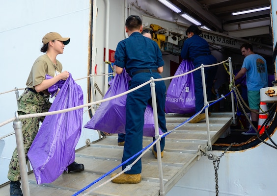 U.S. Navy Sailors participate in a working party to onload mail onto the hospital ship USNS Mercy (T-AH 19) during Pacific Partnership 2024-1 while anchored off Honiara, Solomon Islands, Dec. 1, 2023. Pacific Partnership, now in its 19th iteration, is the largest multinational humanitarian assistance and disaster relief preparedness mission conducted in the Indo-Pacific and works to enhance regional interoperability and disaster response capabilities, increase security stability in the region, and foster new and enduring friendships. (U.S. Navy photo by Mass Communication Specialist 2nd Class Celia Martin)