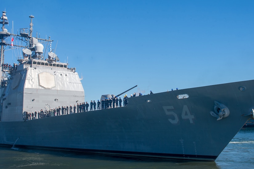 Sailors stand on the flight deck of a Navy ship.