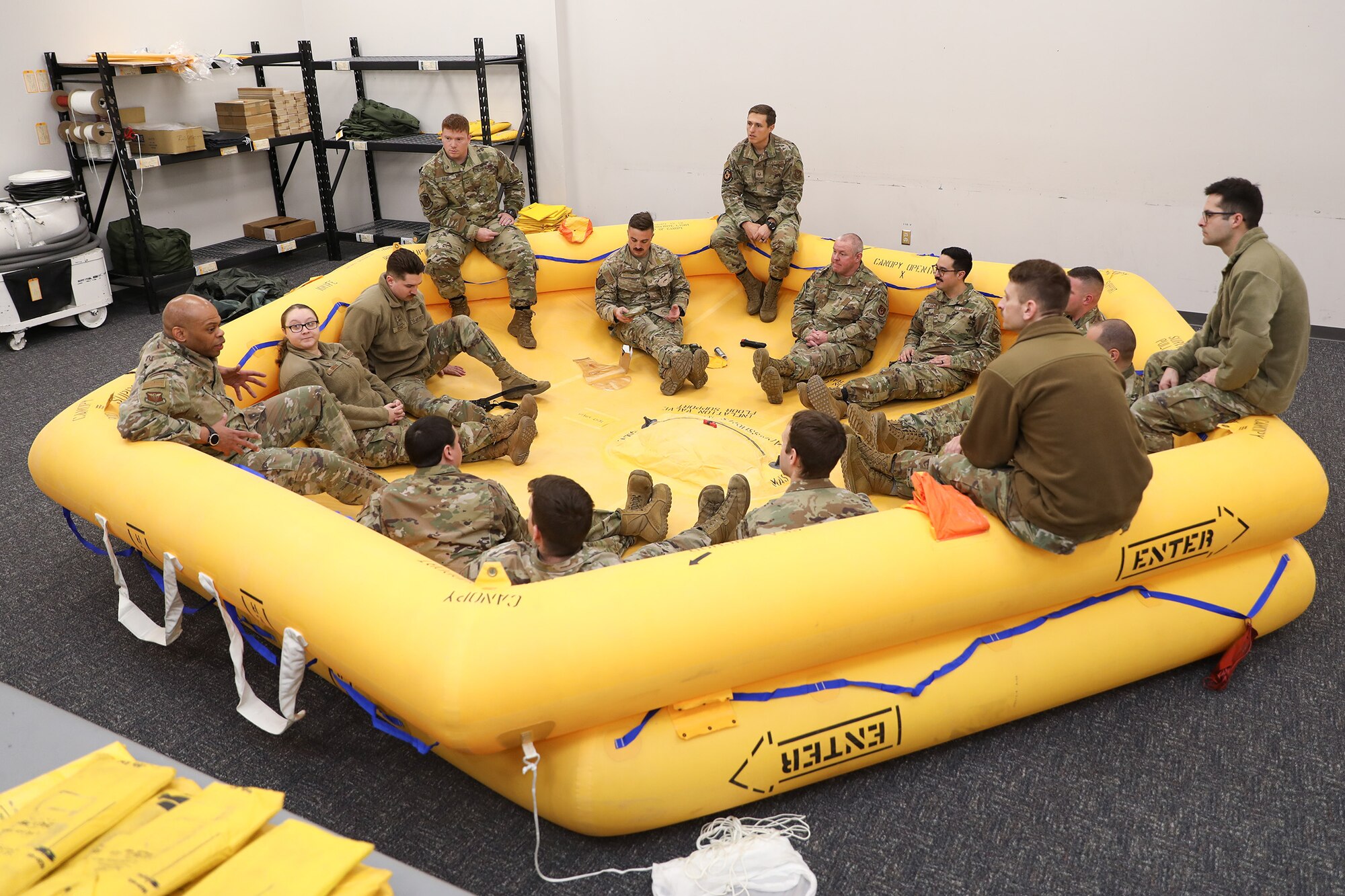 Chief Master Sergeant Travon Dennis, Fourth Air Force command chief, March Air Reserve Base, California, sits with 445th Airlift Wing members in a 46-man life raft as they discuss life saving devices and methods. The members discussed signaling and recovering techniques for downed aircraft in a water scenario, Jan. 6, 2024. The chief master sergeant also met with the 445th's Chief's Group, Rising Six, First Sergeant Council and wing units during his visit at Wright-Patterson Air Force Base, Ohio, Jan. 6-8. 2024. (U.S. Air Force photo/Senior Airman Angela Jackson)