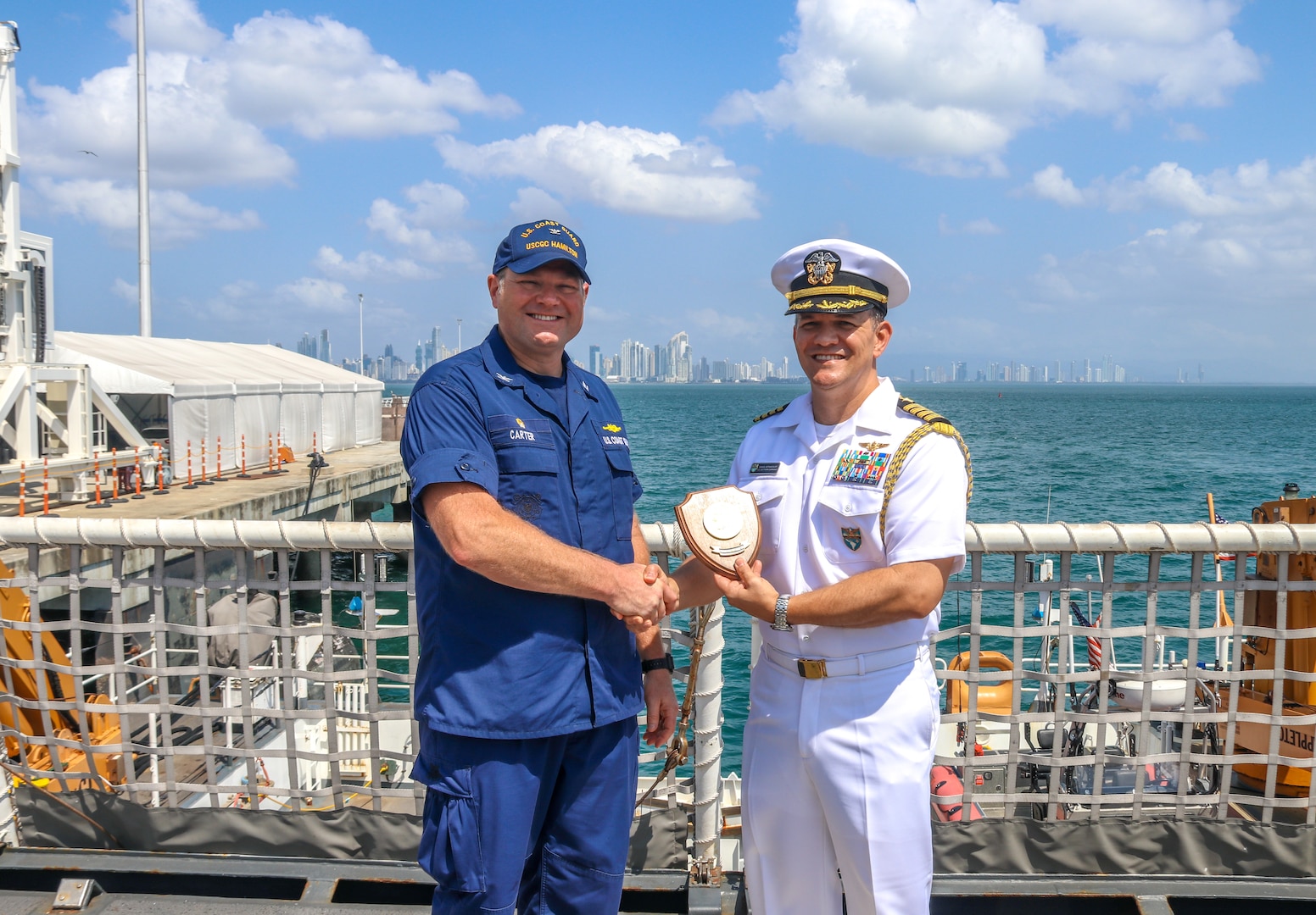 U.S. Coast Guard Capt. Justin Carter, left, the commanding officer of Coast Guard Cutter Hamilton (WMSL 753), shakes hands with U.S. Navy Capt. Dan Betancourt, right, senior defense official Panama, in Panama City, Panama, Jan. 24, 2024. Hamilton became the first U.S. government vessel to moor at the newly constructed Amador cruise terminal.