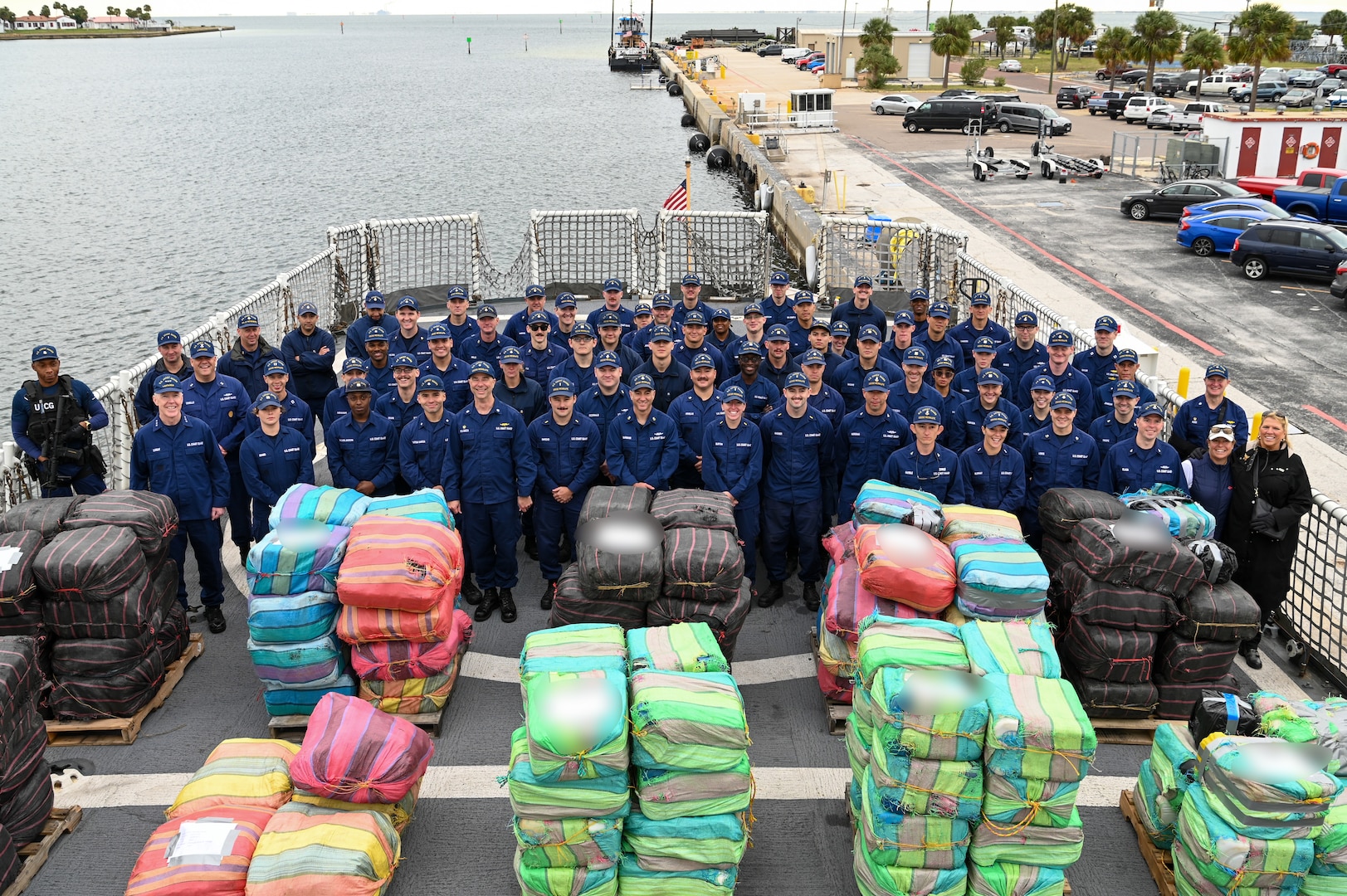 The crew of the Coast Guard Cutter Resolute pose in front of interdicted drugs, Jan. 29, 2024, in St. Petersburg, FL. Drug interdiction is one of the 11 statutory missions of the Coast Guard. (U.S. Coast Guard photo by Petty Officer 3rd Class Nicholas Strasburg)