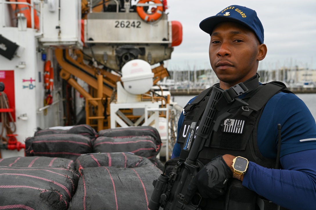 A crew member of the Coast Guard Cutter Resolute stands watch over illegal narcotics, Jan. 29, 2024, in St. Petersburg, FL. Armed Coast Guardsmen stand watch over interdicted drugs to ensure security and accountability of seized contraband. (U.S. Coast Guard photo by Petty Officer 3rd Class Nicholas Strasburg)