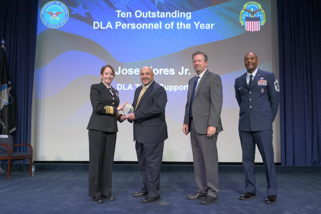 Four people stand on stage during an awards ceremony.